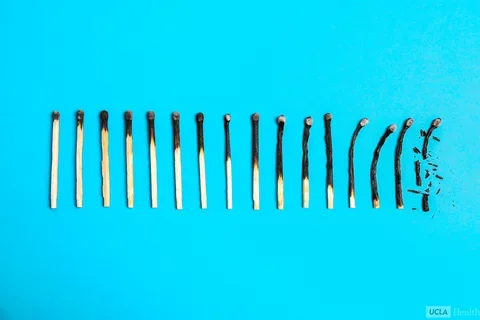 A series of matches laid on a blue background. Each match going right is progressively more burnt than the last.