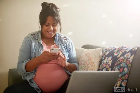 Woman on a couch reading a message on her cellphone.