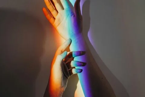 hands lit by a rainbow