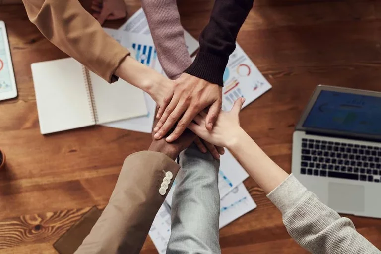 diverse team all placing their hands together