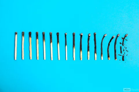 A series of matches laid on a blue background. Each match going right is progressively more burnt than the last.