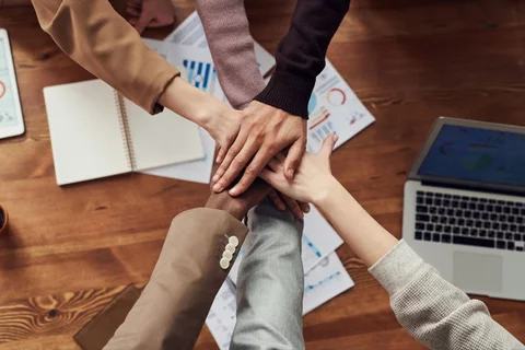 diverse team all placing their hands together